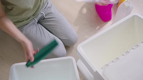 Woman Sorting Colorful Plastic Bottles for Recycling at Home