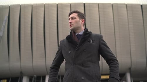 Man in Coat Stands by Modern Urban Building