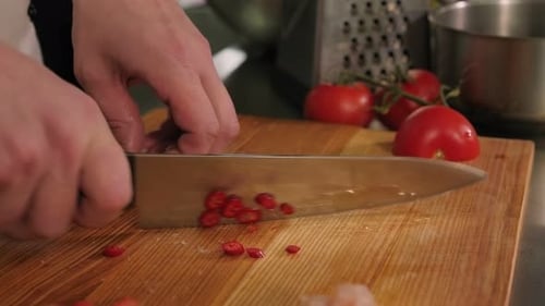 Chef Slices Red Chili Pepper in Kitchen