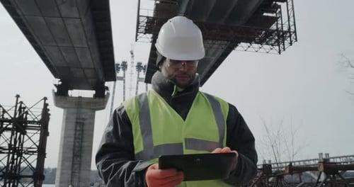 Man Using Tablet on Bridge Construction Site
