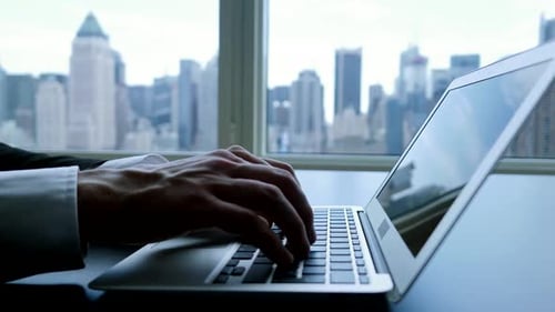 Hands Typing Laptop at City View Office