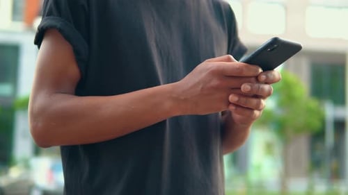 Close Up Male Standing on the Street Typing on Smartphone