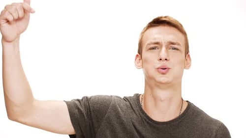 Emotionaler junger gutaussehender Mann schreit mit dem Finger weg auf weißem Hintergrund