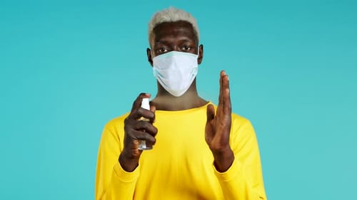 Young Adult Man Sanitizing Hands with Face Mask