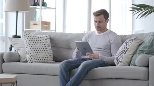 Man Using Tablet While Relaxing on Couch