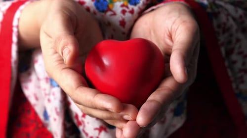 Hands Holding Red Heart Shape Object