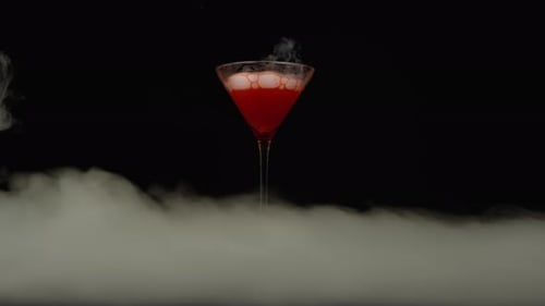 Wrapped Hand Holding Red Cocktail Against Black