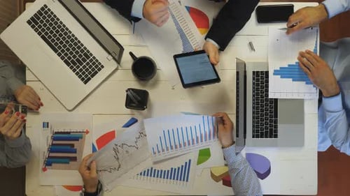 Male and Female Hands of Young Colleagues Examining Financial Graphs at Office