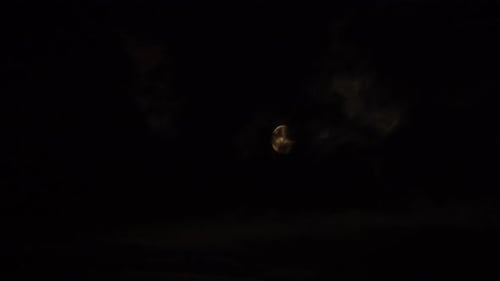 Dunkle Wolken ziehen nachts vor einem hellen Vollmond vorbei.