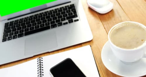 Laptop with Green Screen and Coffee on Desk
