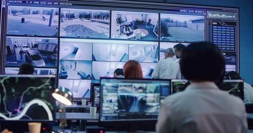 Man Working in Surveillance Center Near Bosses Discussing Footages