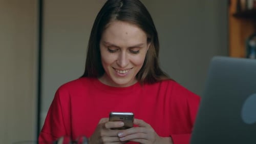 Woman Smiles While Using Smartphone Indoors