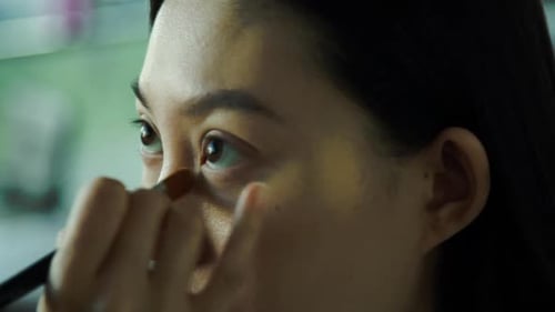 Woman Applies Makeup with Brush for Beauty Routine