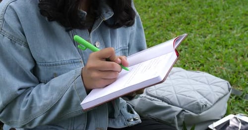Woman Writing in a Notebook on the Grass
