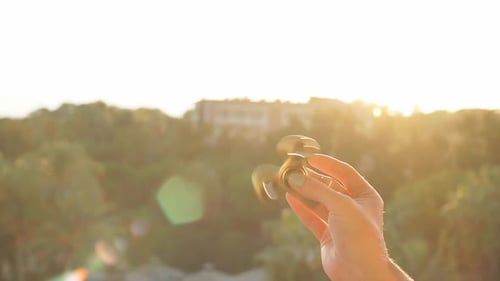 Fille jouant avec Fidget Spinner au coucher du soleil.