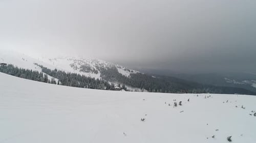 Fly over mountain slope with skiers