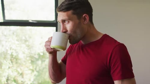 Man Drinking From Mug By Window Indoors