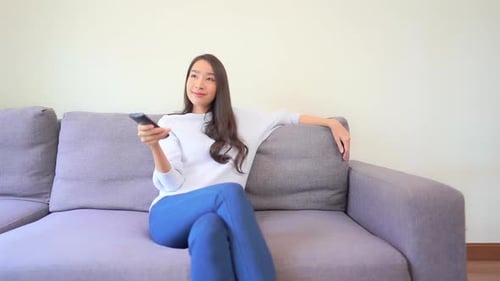 Woman Sits on Couch Watching TV