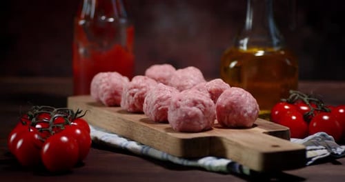 Raw Meatballs and Fresh Tomatoes on Cutting Board