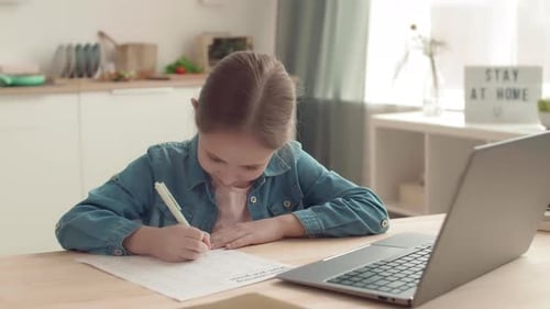 Child Completing Math Worksheet at Home Desk