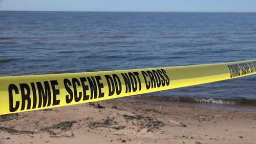 Crime Scene Tape on Sandy Beach Near Ocean