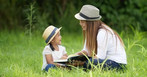 Woman and Child Reading Together in Grassy Field