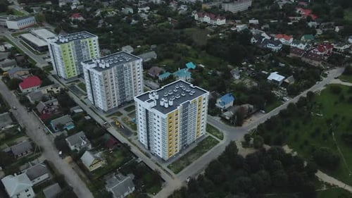 City block. Modern multi-storey buildings among cottages. Flying at dusk at sunset.