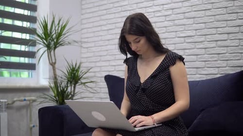 Woman Using Laptop on Couch in Bright Living Room