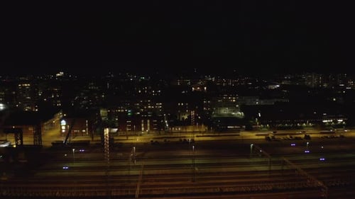 Drohnenschuss von leerem Eisenbahndepot und Autos fahren nachts auf der Stadtstraße.
