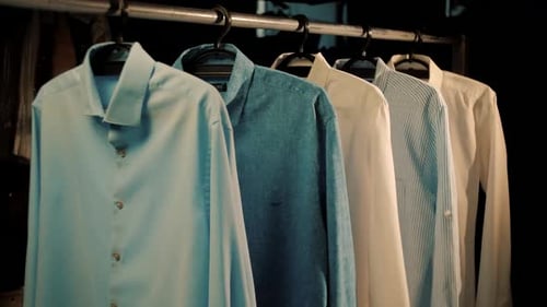 Assorted Shirts Hanging on Rack in Dark Setting