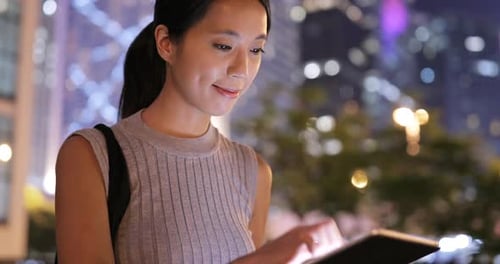 Woman Using Tablet in City at Night