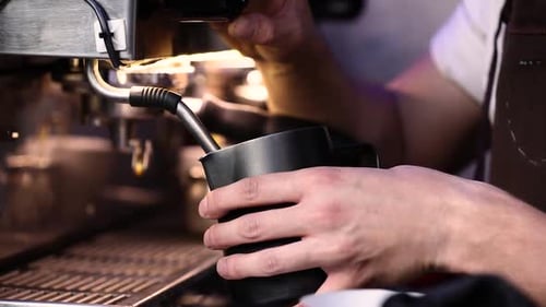 Barista Steaming Milk at Commercial Coffee Machine