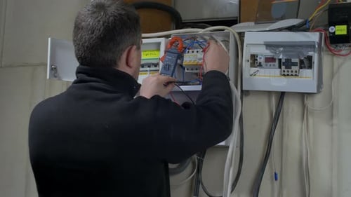 Electrician Inspecting Breaker Box with Voltage Meter