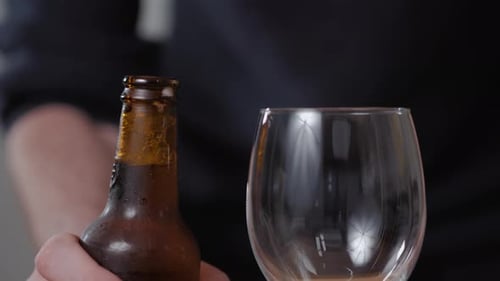 Person Opening and Pouring Brown Beer Bottle