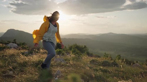 A Girl Tourist in a Yellow Jacket Goes Hiking Along a Mountain Ridge