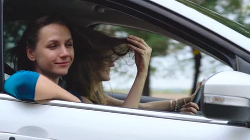 Two Young Women Ride in a Car and Have Fun