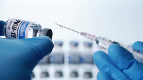Close up, Scientist is holding a glass vial for Covid-19 vaccine and syringe in laboratory.
