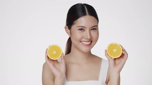 Cute female model clean fresh skin is holding an orange. Expressive facial expressions. Cosmetology.