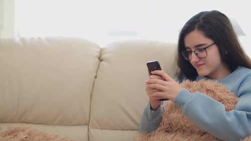 Girl Using Smartphone Relaxing on the Sofa