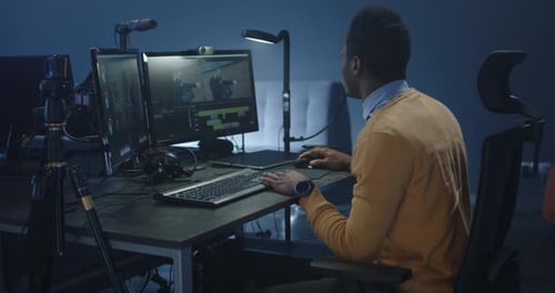 Video Editor Working at Desk in Dark Office