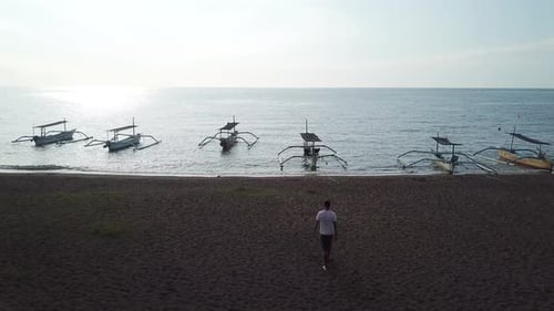 the Guy Walks Along the Beach and Raises His Hands