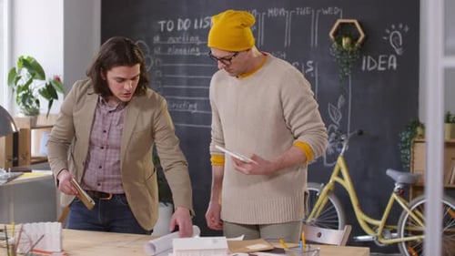 Two Men Collaborate on Plans in Modern Office