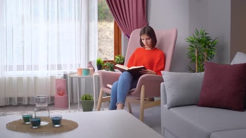 Woman Reading Book in Armchair at Home
