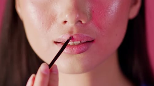 Closeup Shot Of Young Woman Applying Lip Gloss With Makeup Brush