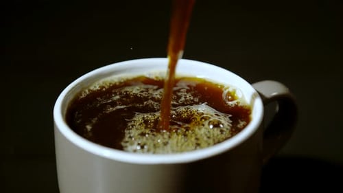 Pouring Dark Coffee into a White Mug