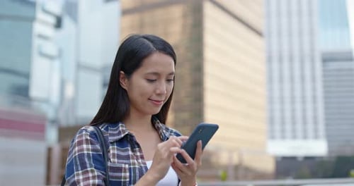 Une femme utilise un téléphone portable pour envoyer des SMS en ville