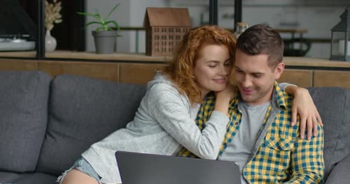 Couple Cuddling and Watching Laptop at Home