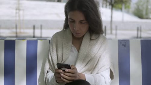 Woman Using Smart Phone on City Bench