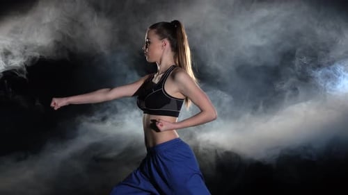 Young Woman Practicing Martial Arts in Smoky Studio