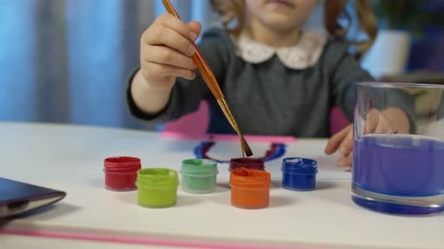 Child Painting with Watercolors at Table Indoors